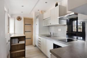 a kitchen with white cabinets and a black counter top at Petit gîte bleu jusqu'à 4 personnes in Huillé