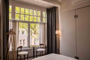 a bedroom with a window and a table and chairs at Hotel By Atelier in Nijmegen