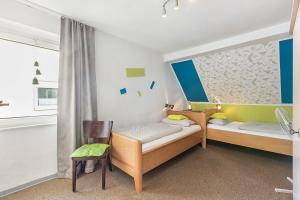 two beds in a room with a chair and a window at Pension Neuenrade in Neuenrade