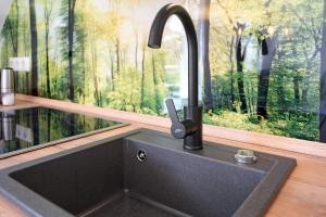 a kitchen sink in front of a window with a forest mural at Ostseerauschen in Hohwacht +79 photos