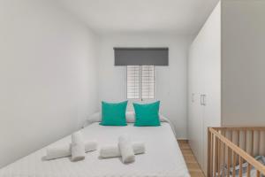 a white bedroom with a bed with green pillows at Encanto Costero in Ayamonte