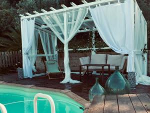 a white pergola with a table and chairs next to a pool at Il Giardino Etrusco Bolsena in Bolsena
