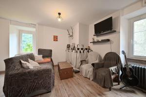 a living room with a couch and a guitar at Pays De L'ours - Pyrénées in Melles