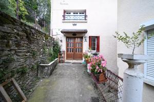 a building with a wooden door and flowers in front of it at Pays De L'ours - Pyrénées in Melles