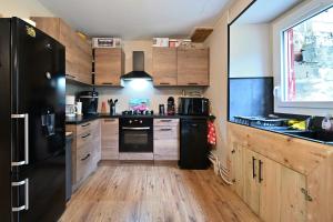a kitchen with a black refrigerator and wooden cabinets at Pays De L'ours - Pyrénées in Melles