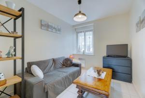 a living room with a couch and a tv at Grain de sable in Saint-Benoît-des-Ondes