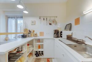 a kitchen with white cabinets and a sink at Grain de sable in Saint-Benoît-des-Ondes