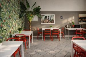 a restaurant with white tables and red chairs at Koala Hostel in Milan