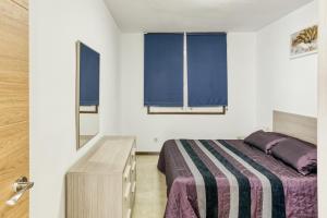 a bedroom with a bed and a dresser and two windows at San Enrique in L'Escala +18 photos