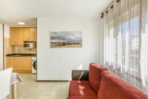 a living room with a red couch and a kitchen at San Enrique in L'Escala