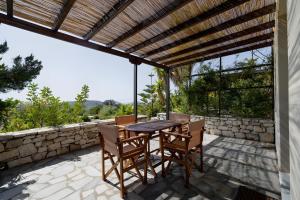 a patio with a table and chairs and a stone wall at Kythiris Studios in Kálamos Kythira