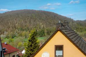 a yellow house with a mountain in the background at Gemütliche Ferienhaus am Main in Gemünden