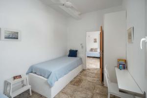 a white bedroom with a bed and a desk at House Avlomonas in Livadi