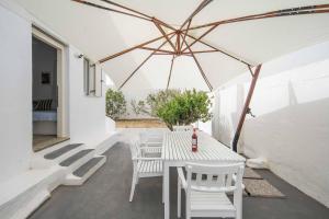 a white patio with a table and chairs and an umbrella at House Avlomonas in Livadi