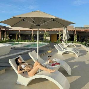 a woman laying on a chair next to a pool at Apec Beach Luxury Mũi Né in Mui Ne
