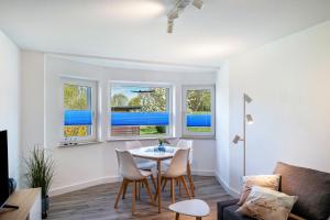 a living room with a table and chairs and windows at Strandnahe Fewo 1 in Dierhagen