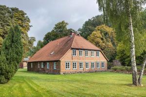 a large brick building with a roof on a grass field at Hof Hohe Eichen in Göhrde