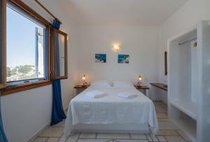 a white bedroom with a bed and a large window at Maria's Village Suite in Kampos Paros