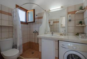 a bathroom with a toilet a sink and a washing machine at Maria's Village Suite in Kampos Paros