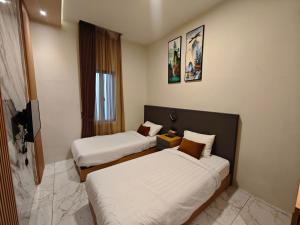 a hotel room with two beds and a television at AIRO Villas in Sultan Syarif Kasim II International Airport