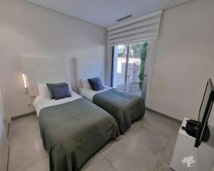 two beds in a room with a tv and a window at Tipuana 7 in Orihuela
