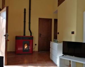 a living room with a red stove in a room at El Aterpe 4 in Aldehuela del Rincón