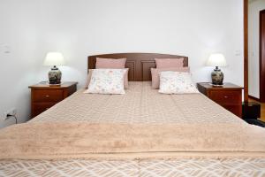 a bedroom with a large bed with two lamps at Casa da Cândida in Nazaré