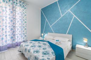 a bedroom with a bed with a blue wall at Le Quattro Perle Apartments in Pachino