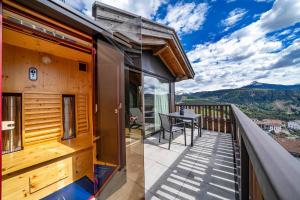 a wooden house with a balcony with a table at Chalet Schlossberg Schwarzhorn in Nova Ponente