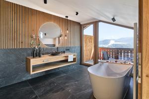 a bathroom with a tub and a sink and a mirror at Chalet Schlossberg Schwarzhorn in Nova Ponente +18 photos