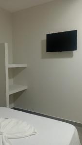 a bedroom with a bed and a tv on a wall at Hotel AG3 in Teixeira de Freitas