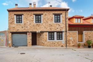 a brick house with a garage in front of it at Casa Rural Doña Manuela in Valdemierque