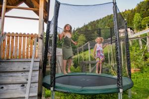 a woman and a little girl standing on a trampoline at Lechnerhof Appartement Alpenrose in Schenna