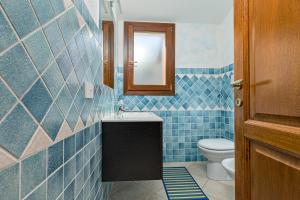 a blue tiled bathroom with a toilet and a mirror at Villetta Lu Lioni in San Teodoro