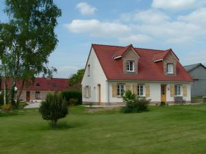 a house with a red roof on a green yard at Grand Gîte Avec 2 Chambres in Saint-Pol-sur-Ternoise