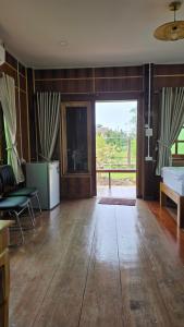a living room with wooden floors and a large sliding glass door at ฮักจังโฮมสเตย์ ที่พักแม่แตง in Chiang Mai
