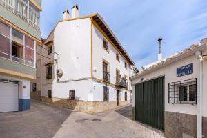 a white building with a green door in a street at Lavanda in Hinojares