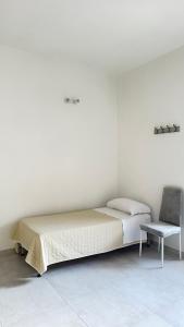 a white bedroom with a bed and a chair at Casa Vacanze Flora in Peschici +12 photos