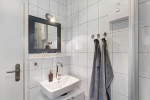 a white bathroom with a sink and a mirror at Idyllic Lakeside Cottage in Bockhorn +16 photos