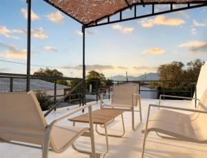 a group of chairs and a wooden table on a balcony at The Beach White House - 80m from the Beach - Renovated in Áyios Yeóryios