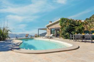 a swimming pool with a table and chairs next to a house at Villa Bumortu in Olmeto +5 photos