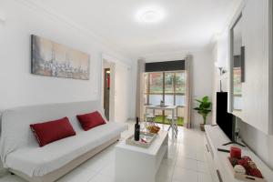 a living room with a white couch and red pillows at Apartamento El Tute in Bajamar