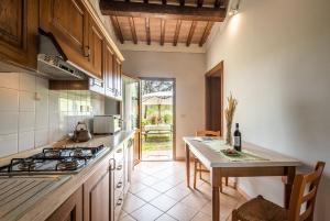 a kitchen with a stove and a table with a bottle of wine at Faetino - Gallo in Colle di Val d'Elsa