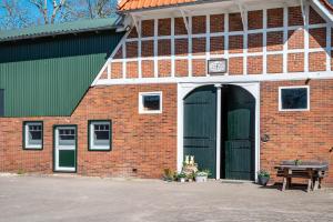 a red brick building with green doors and a table at Fewo Heimathafen in Osterbruch