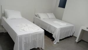 two beds with white linens in a room at Hotel AG3 in Teixeira de Freitas