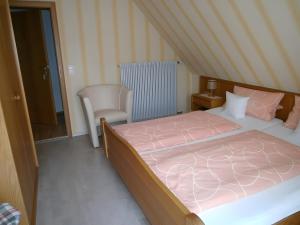 a bedroom with a large bed and a chair at Gästehaus Fischerhäusle in Mitten