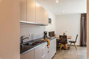 a kitchen with a sink and a table with chairs at Aster Moments Apt Moritz in San Genesio Atesino