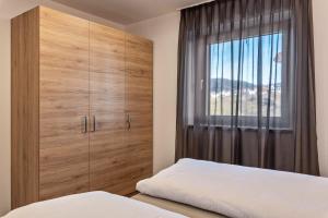 a bedroom with a large wooden cabinet and a window at Aster Moments Apt Moritz in San Genesio Atesino