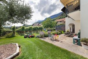 a backyard with a lawn with a table and chairs at Apartment Weingut Zail in Appiano sulla Strada del Vino