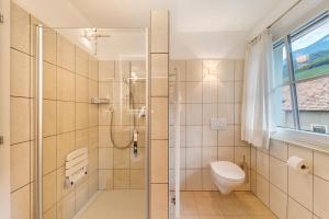 a bathroom with a shower and a toilet and a window at Apartment Weingut Zail in Appiano sulla Strada del Vino +25 photos